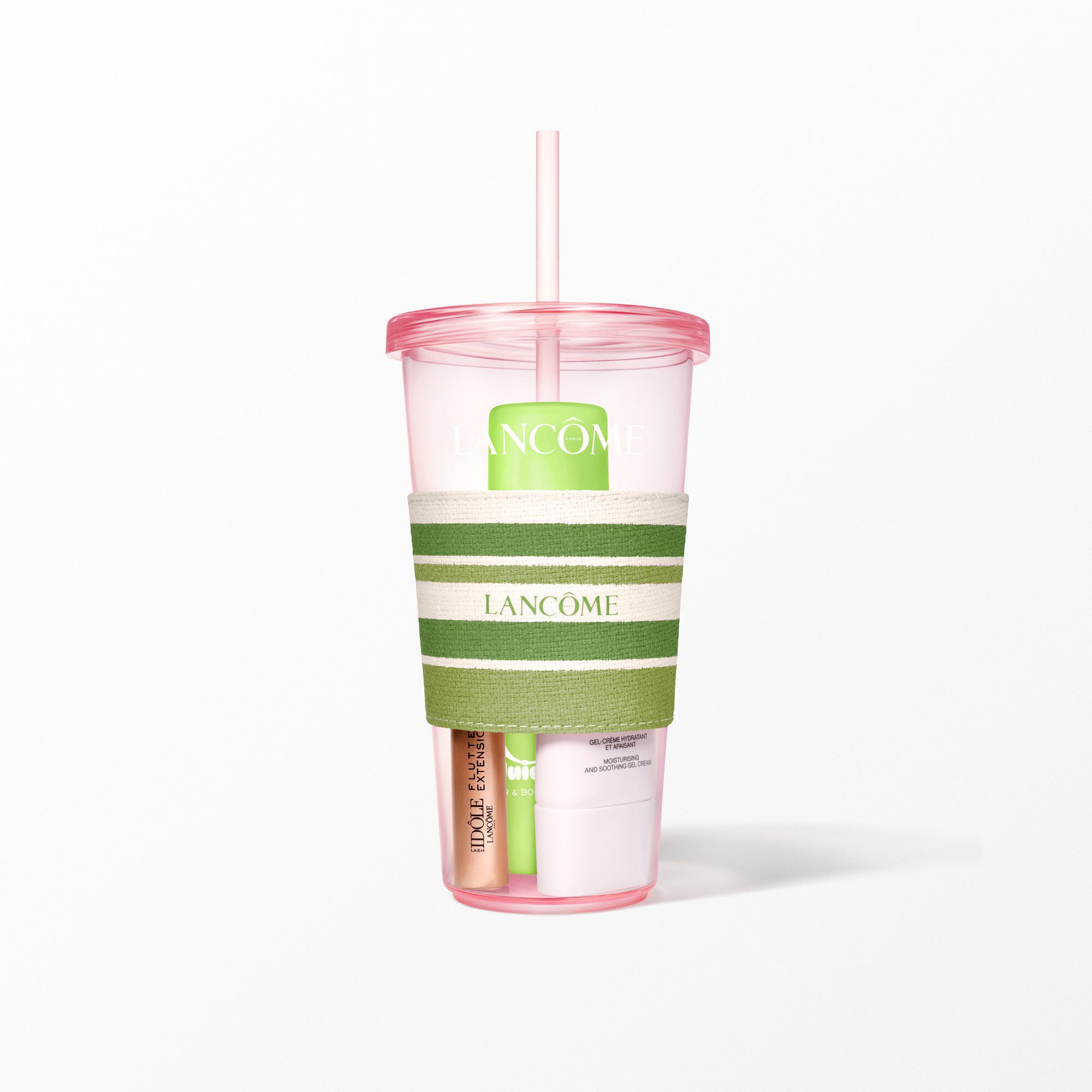 A close-up of the pink Lancome tumbler with a green and white striped sleeve holding beauty products.