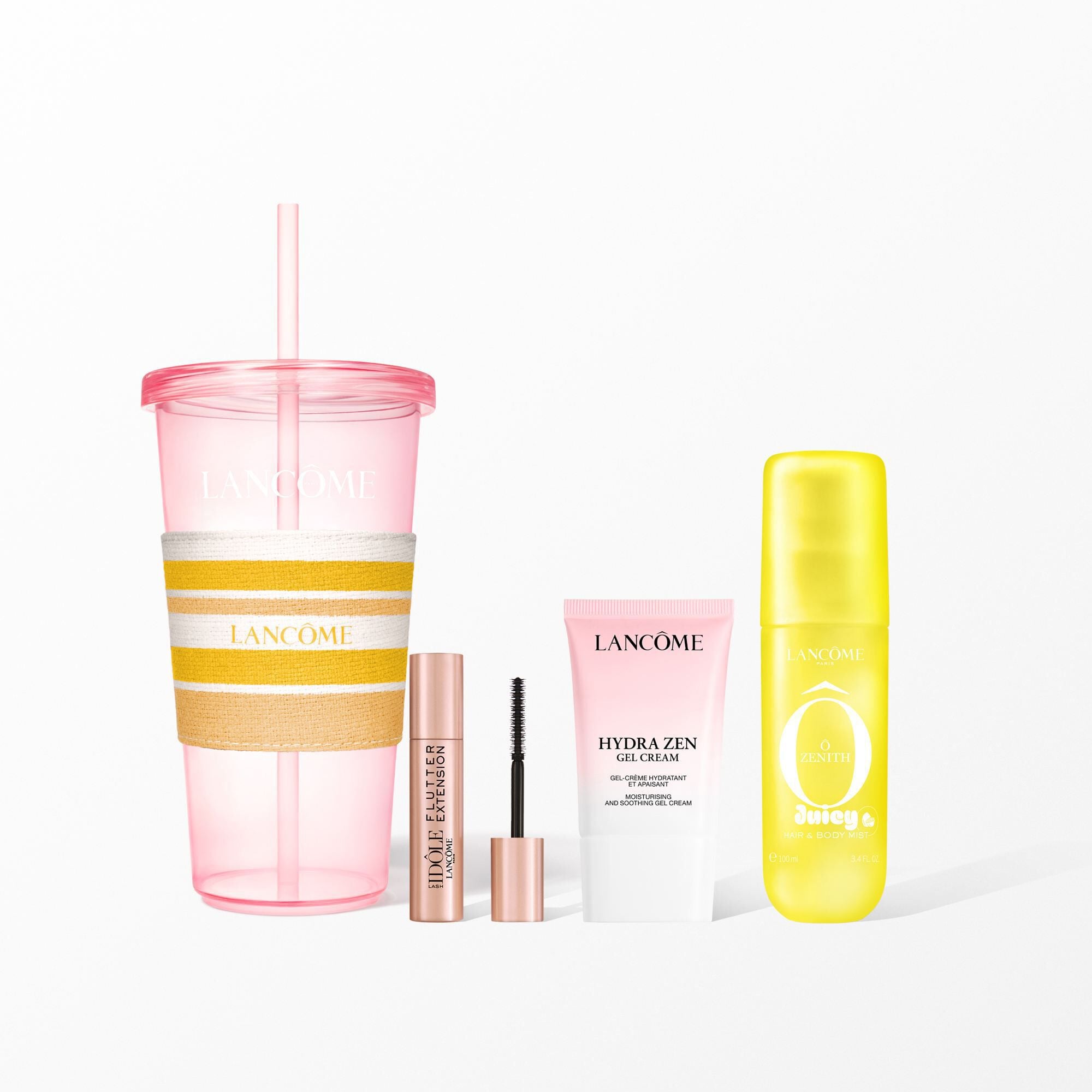 A Lancome beauty set featuring a pink reusable tumbler with a yellow striped sleeve, mascara, face cream, and a yellow hair and body mist.