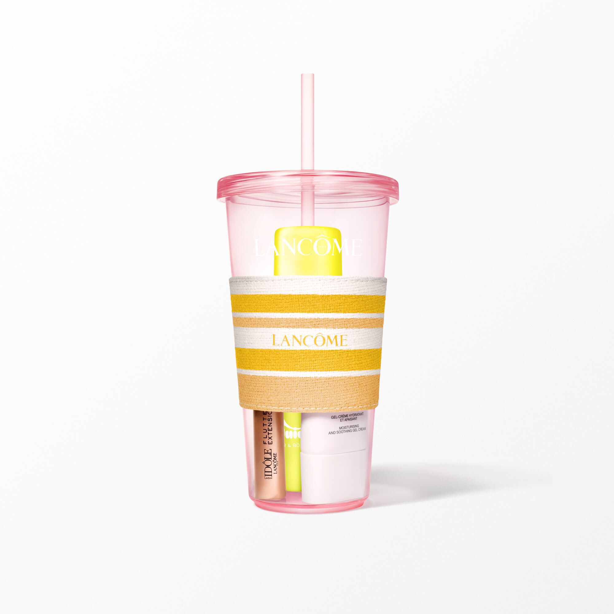 A close-up of the pink Lancome tumbler with a yellow and white striped sleeve holding beauty products.